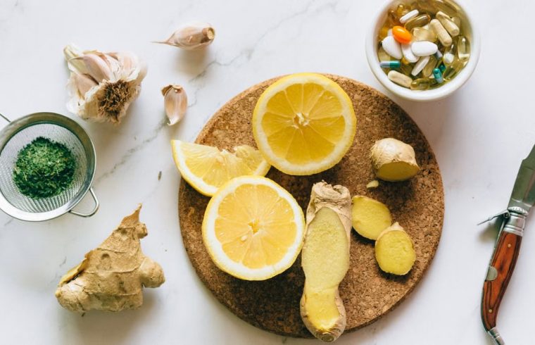 Flat lay of natural remedies including lemon, ginger, and garlic alongside pills.